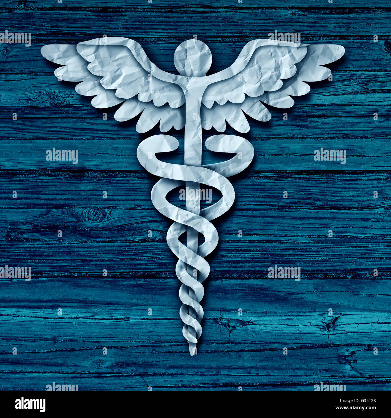 Medical symbol concept as cut crumpled paper shaped as a healthcare treatment icon on old grunge blue wood as a metaphor for hospital care or pharmacy as a photo realistic illustration. Stock Photo
