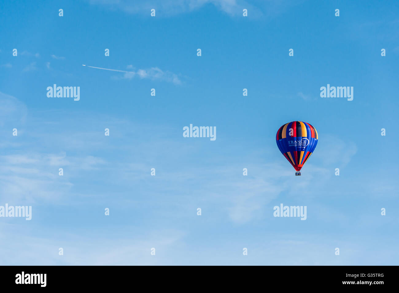 Two contrasting types of air vehicles, a jet airplane and a balloon, on a blue sky background Stock Photo