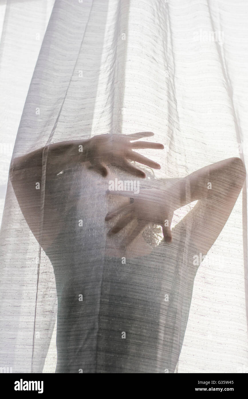Young woman hiding face with hands behind the blinds Stock Photo