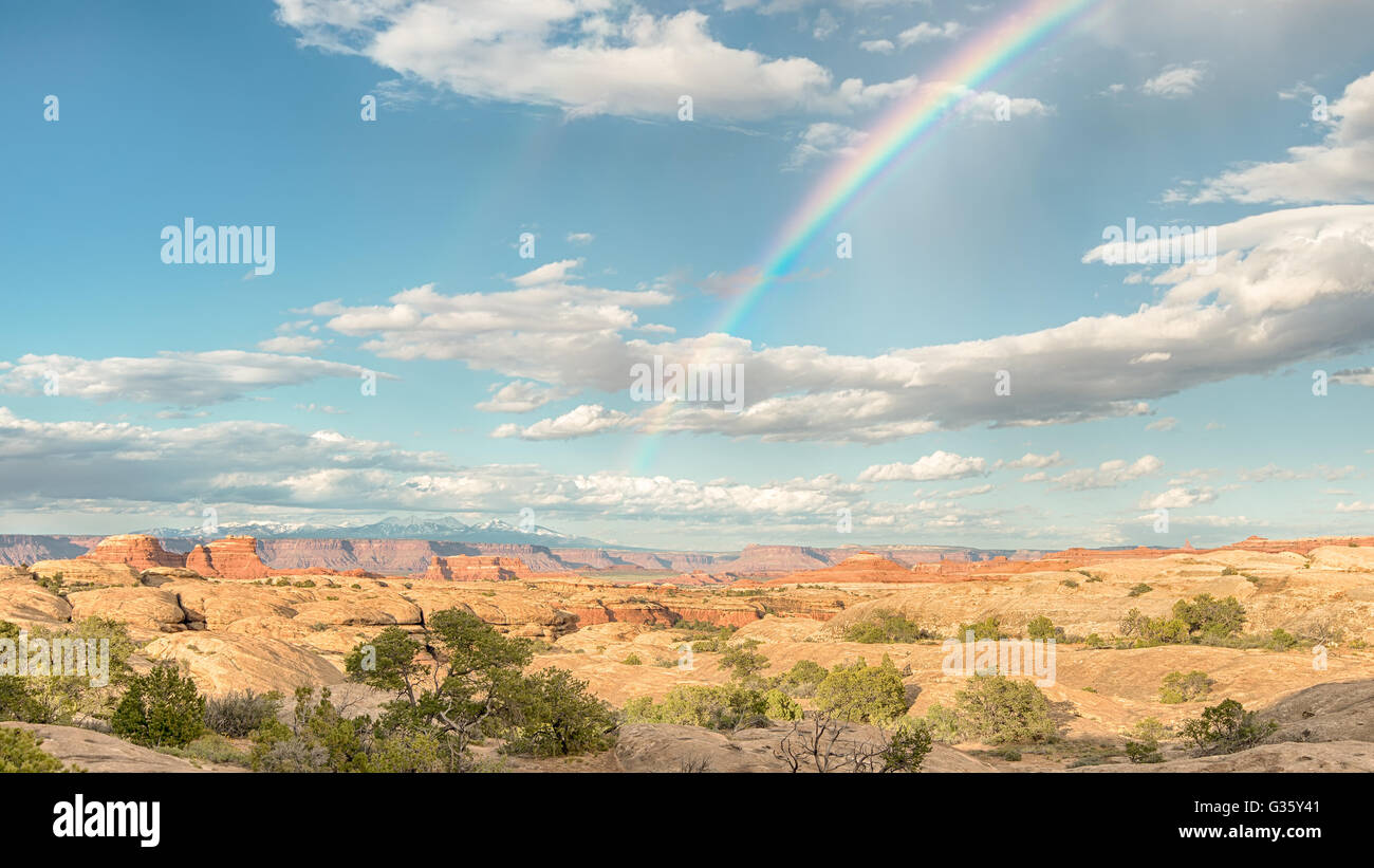 A rainbow arcs across the sky towards the La Sal mountains, in the Needles District of Canyonlands National Park, near Moab, Uta Stock Photo