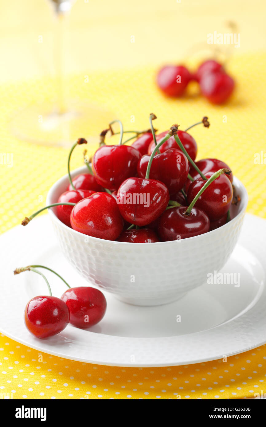 A bowl of fresh red cherries on a yellow background Stock Photo