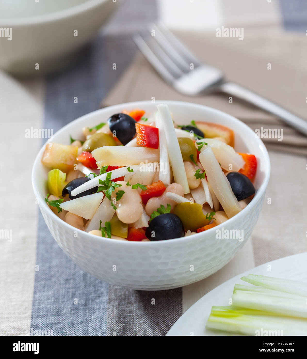 A bowl of bean salad with endive, bell pepper, onion, olives and