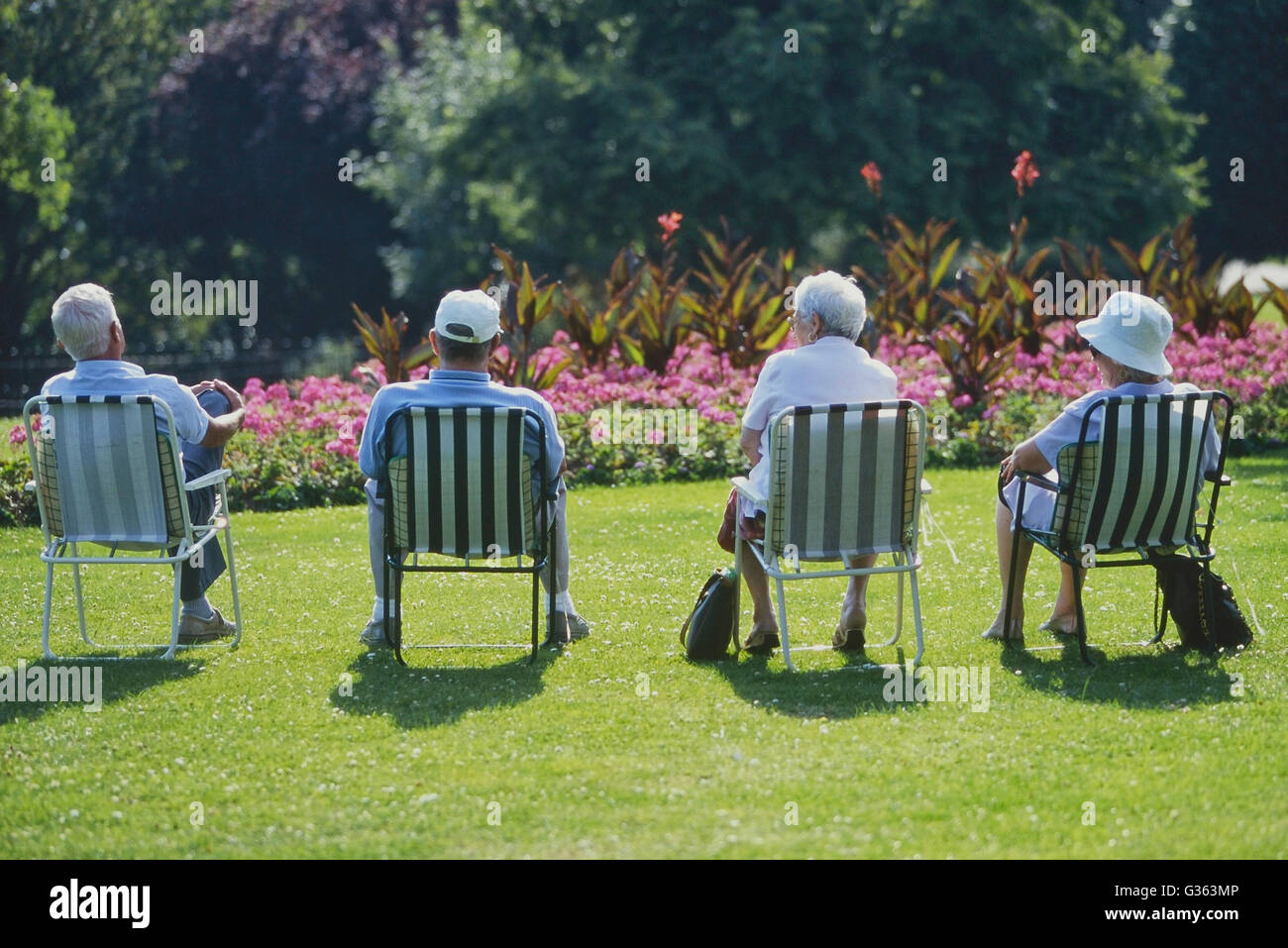 Four pensioners sitting in a row at Southend Cliff gardens, Southend-on-Sea. Essex. England. UK Stock Photo
