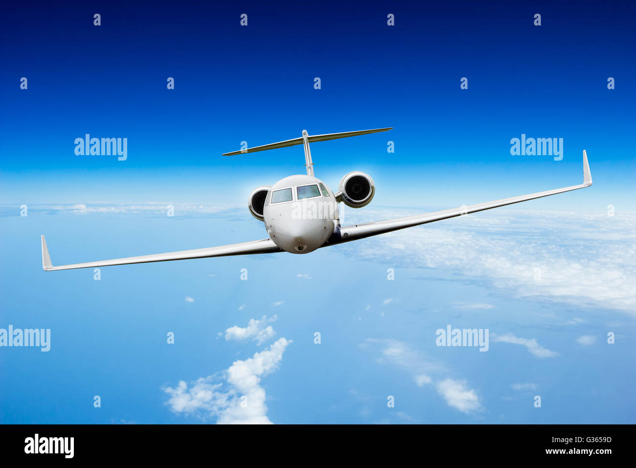 Private jet plane flying above clouds, shot from front view Stock Photo