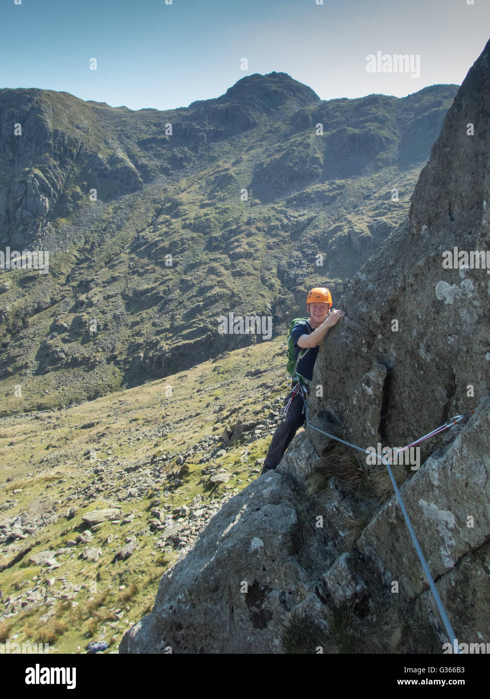 A rock climbing enjoying sunshine on the classic rock climb 'Corvus', at the head of Combe Ghyll, Borrowdale, Lake District National Park, Cumbria Stock Photo