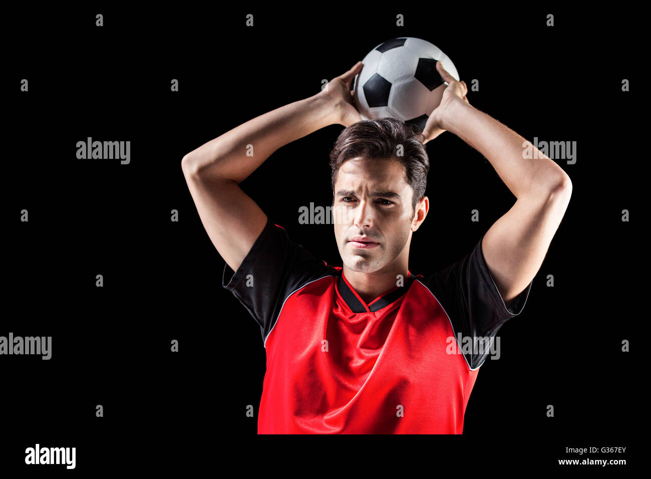 Confident male athlete throwing football Stock Photo