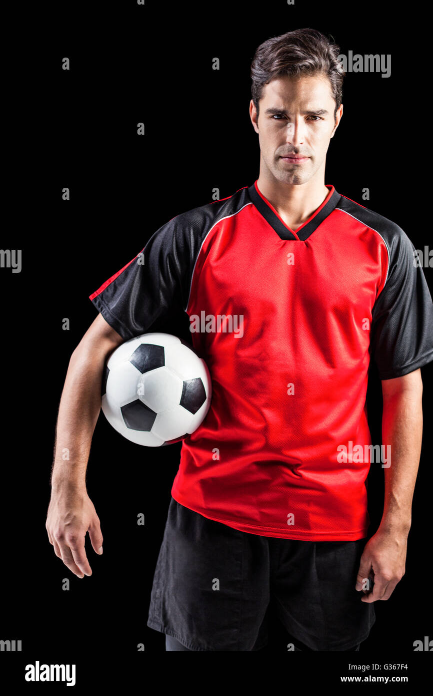 Portrait of confident male athlete holding football Stock Photo