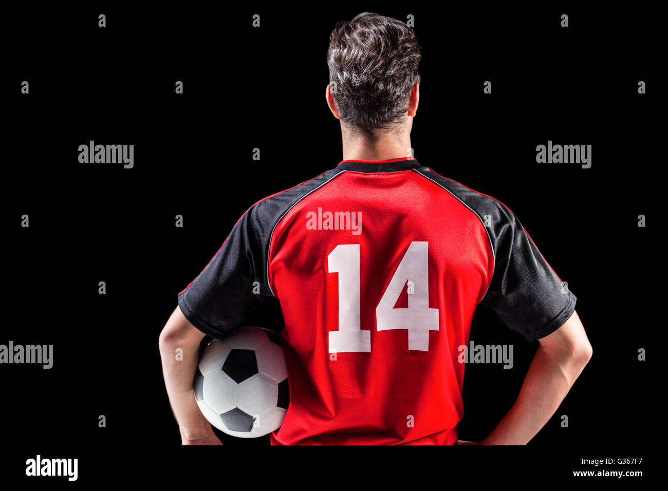 Rear view of male athlete holding football Stock Photo
