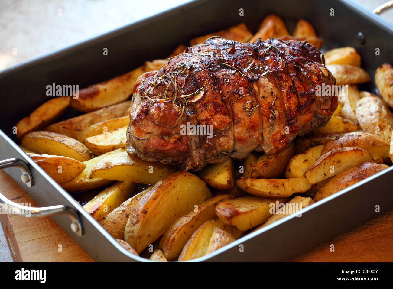Photo of a lamb roast with potatoes in a roasting pan fresh out of the