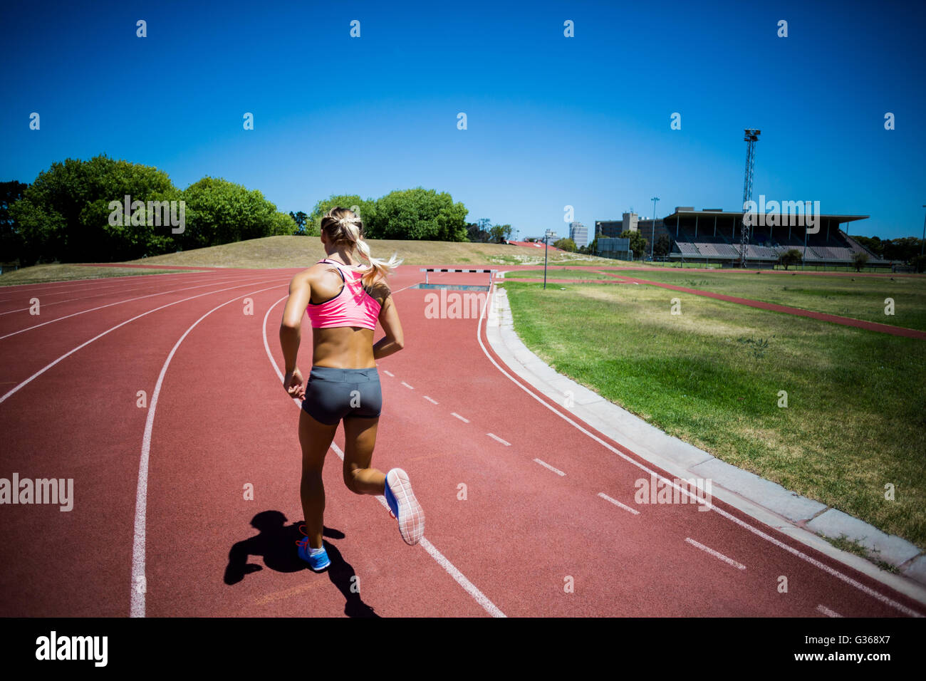 Rear view of female athlete running on the racing track Stock Photo