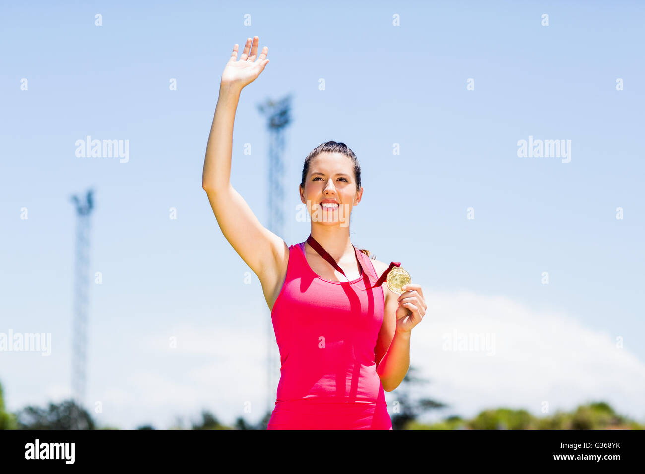 Female athlete waving her hand and showing gold medal Stock Photo
