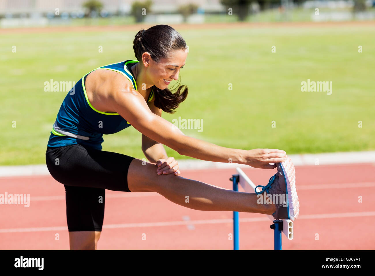 Female athlete warming up above hurdle Stock Photo