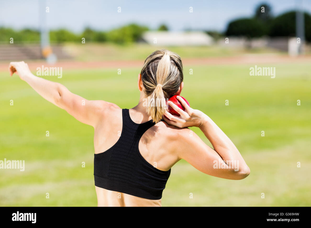 Rear view of female athlete preparing to throw shot put ball Stock