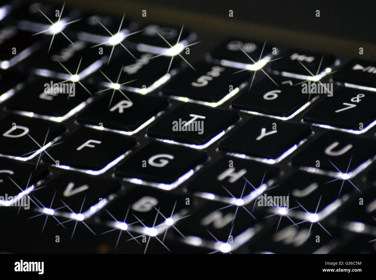 Twinkling back lit keys on a black computer keyboard in close up. Technology concept Stock Photo
