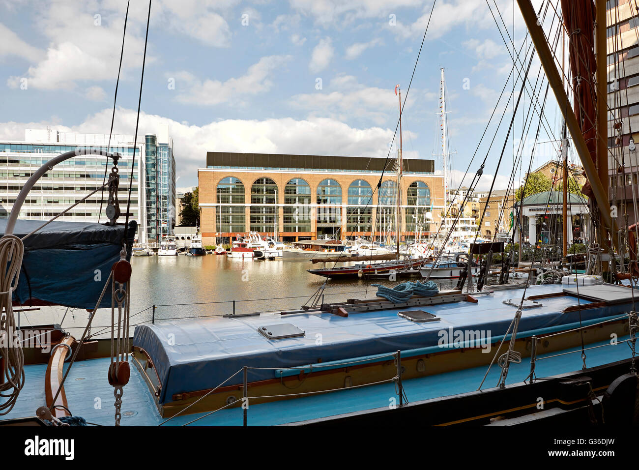 View across marina with barge towards refurbished office building. Commodity Quay, London, United Kingdom. Architect: BuckleyGrayYeoman, 2014. Stock Photo