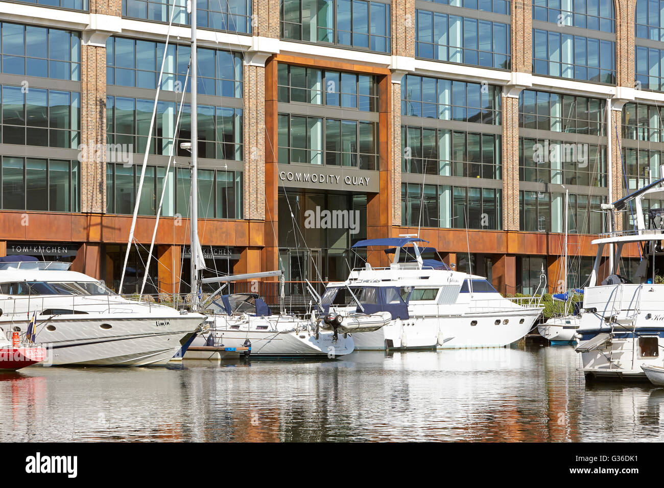 Line-up of yachts in front of building entrance. Commodity Quay, London, United Kingdom. Architect: BuckleyGrayYeoman, 2014. Stock Photo