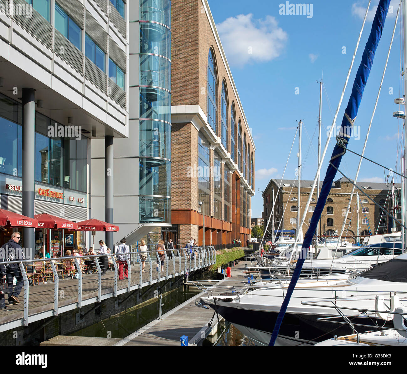 Line-up of yachts in front of building entrance. Commodity Quay, London, United Kingdom. Architect: BuckleyGrayYeoman, 2014. Stock Photo