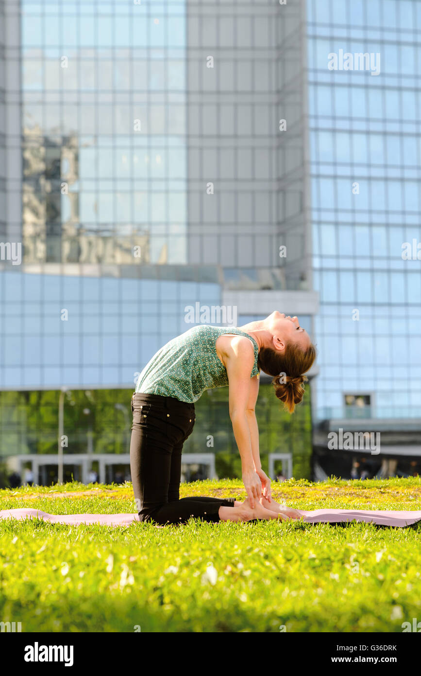 Yoga training as asana posture of young woman in business suit in Moscow Stock Photo