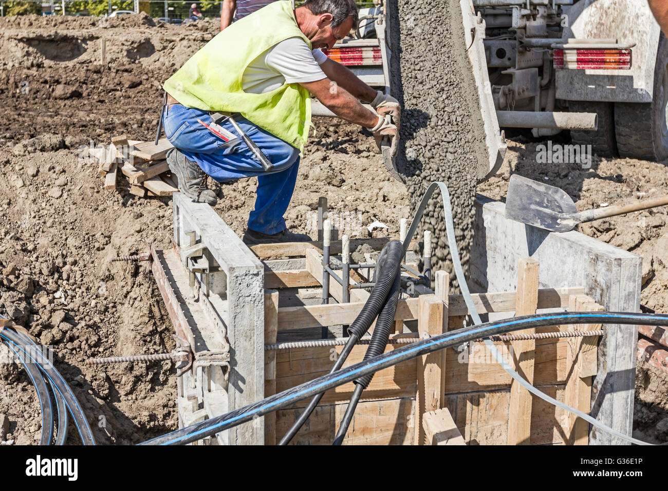 Workers at building site are pouring concrete in mold made of wood
