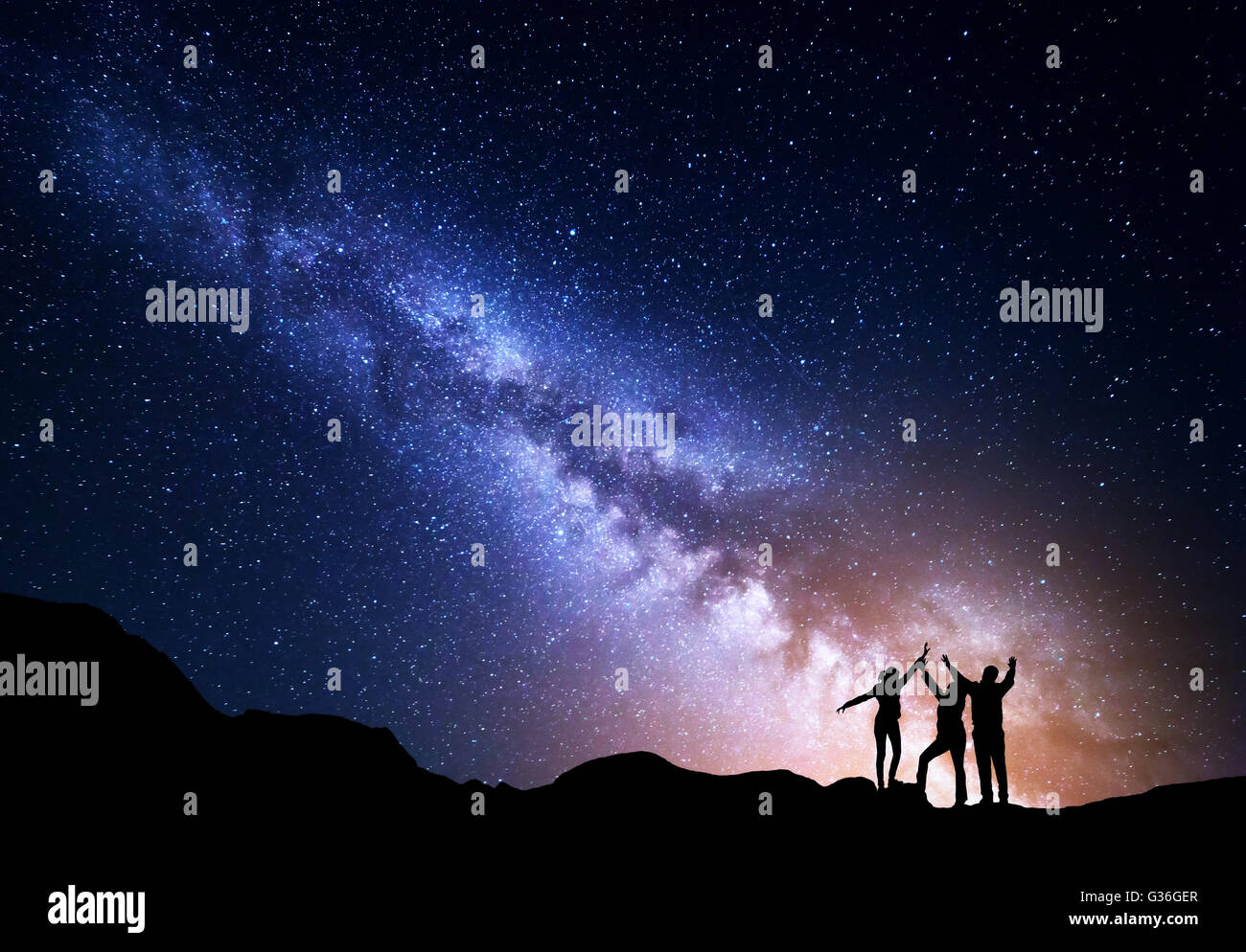 Landscape with colorful Milky Way and yellow light. Night starry sky with silhouette of a sporty happy family with raised-up arm Stock Photo