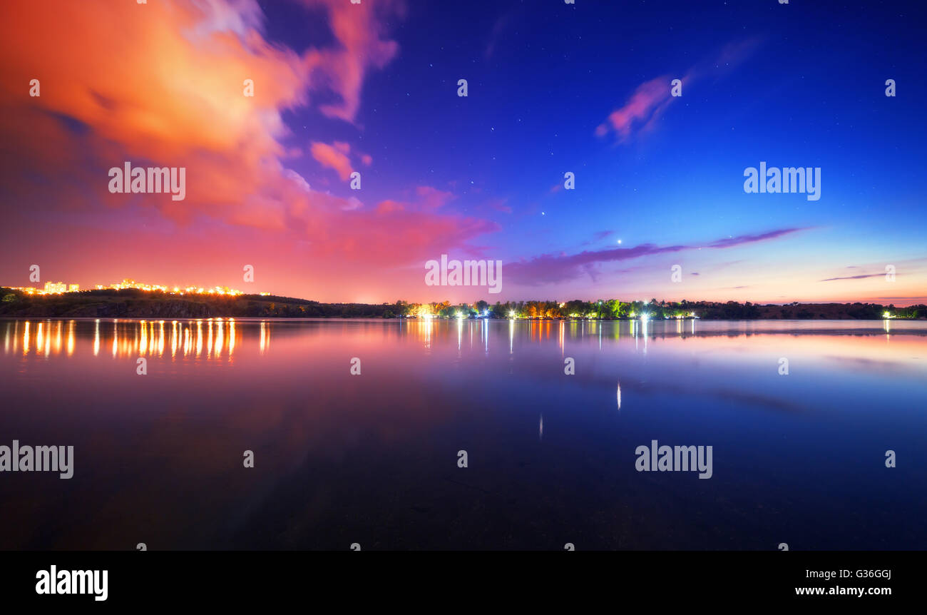Colorful night landscape on the lake with blue sky and moving clouds reflected in water. Nature background Stock Photo