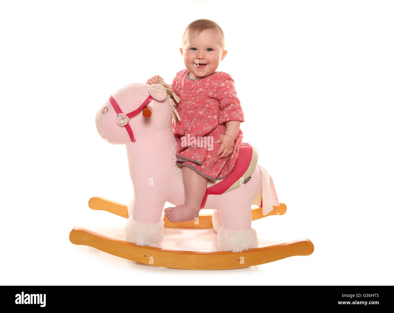 Baby girl playing on a rocking horse cutout Stock Photo