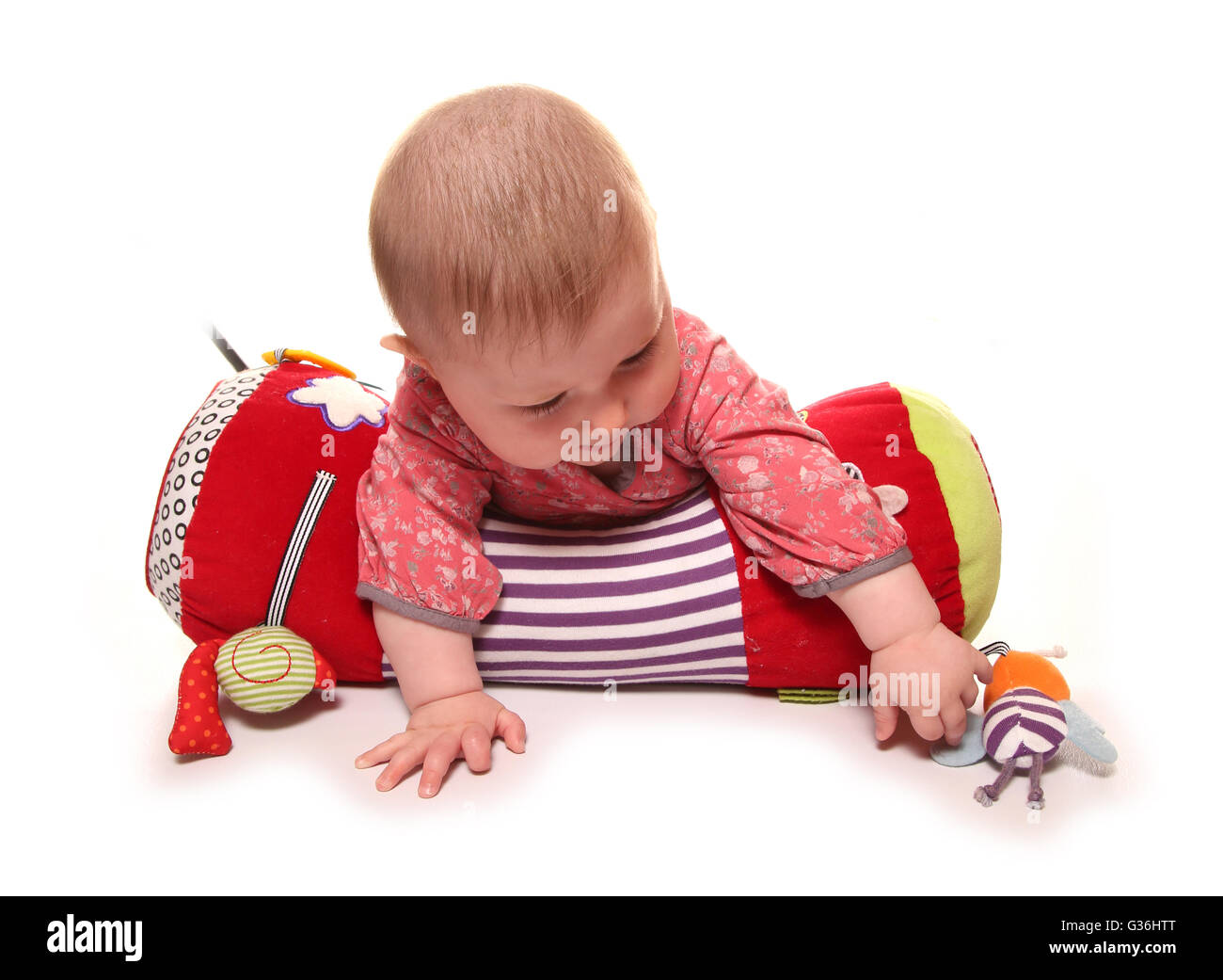 baby girl playing on a tummy time roll cutout Stock Photo