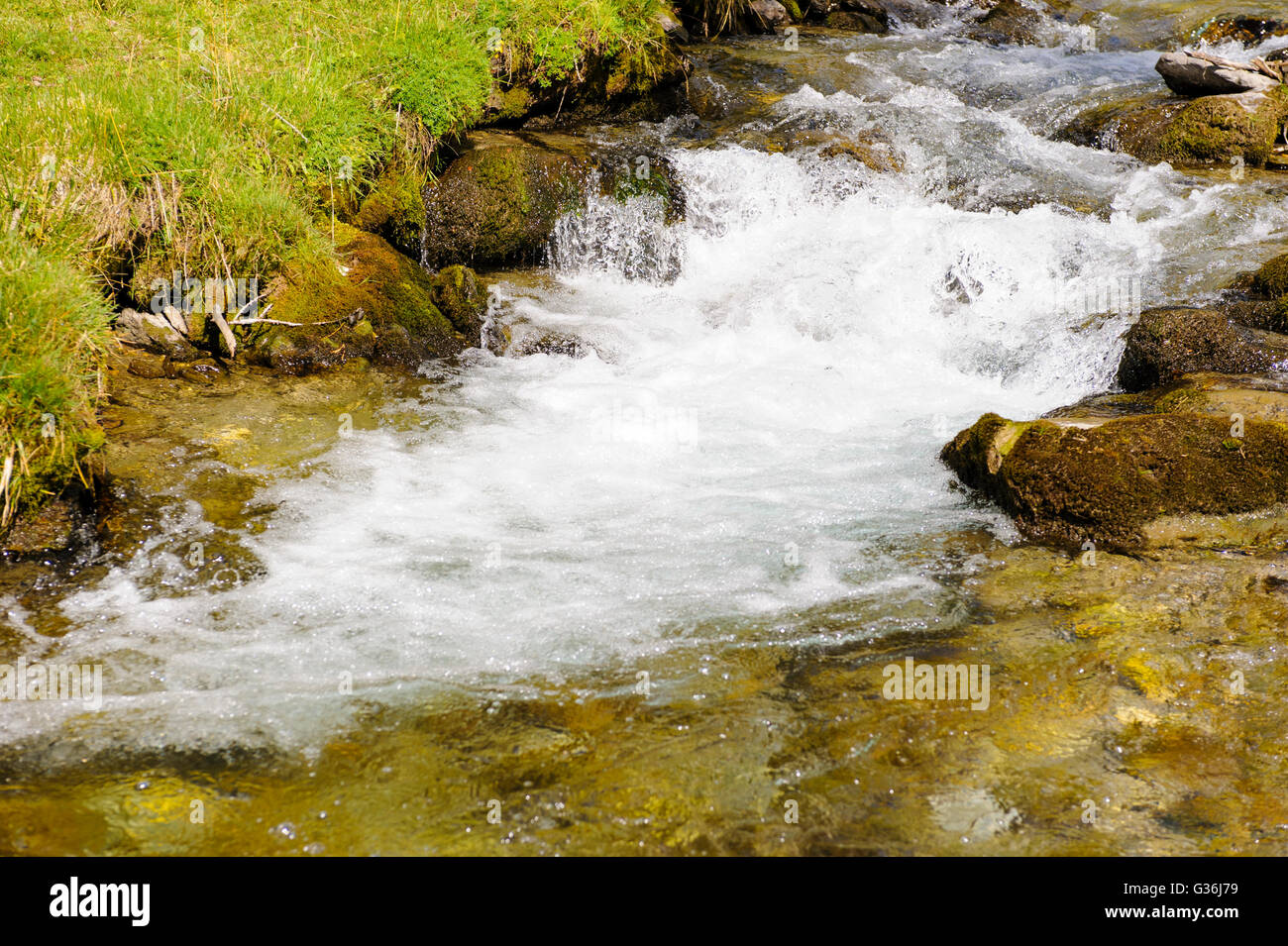 small stream with clear water and cascade in alps mountains Stock Photo