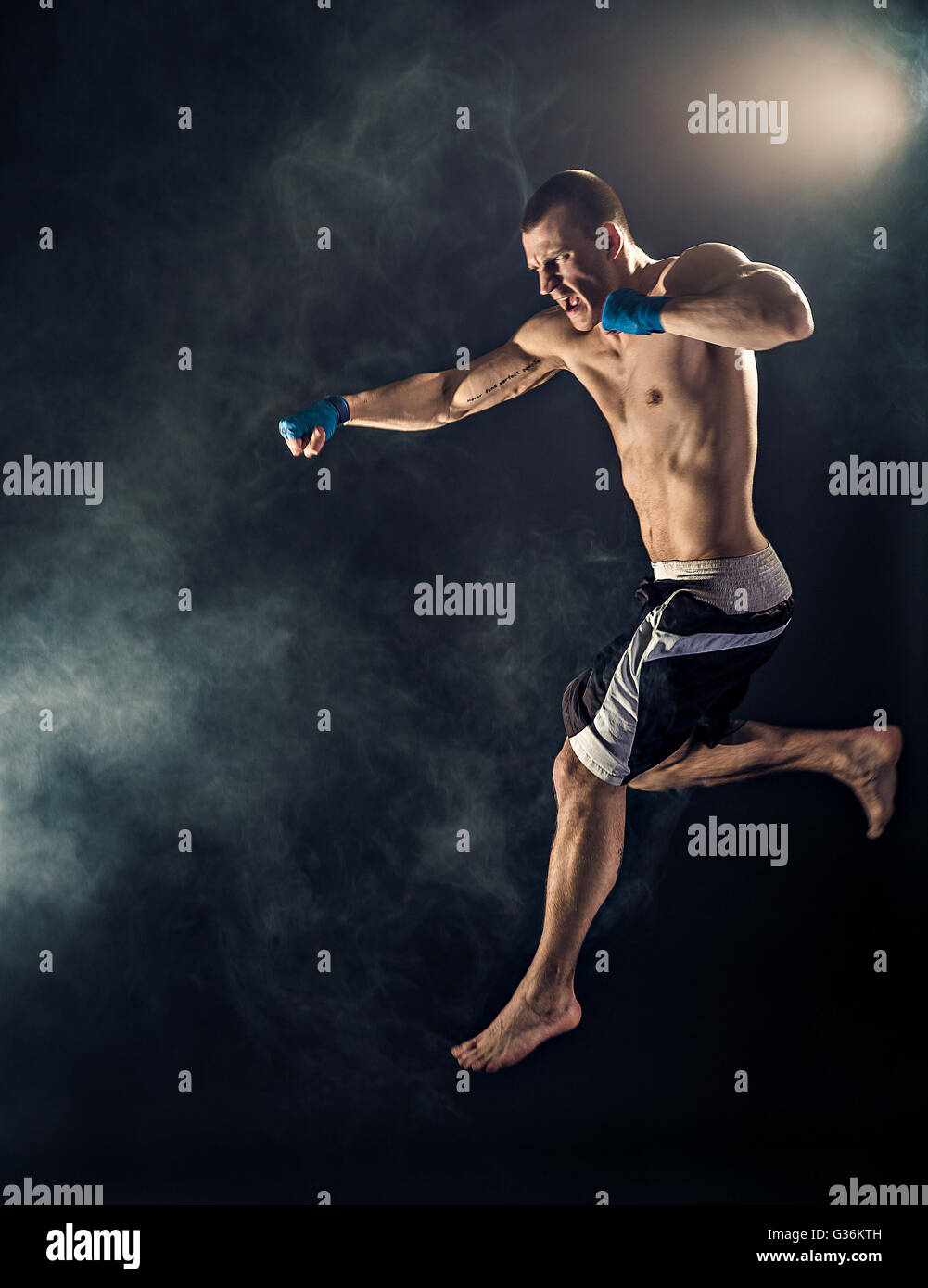 Fighter Jump Muscular kickbox or muay thai fighter punching in jump. Smoke Stock ...