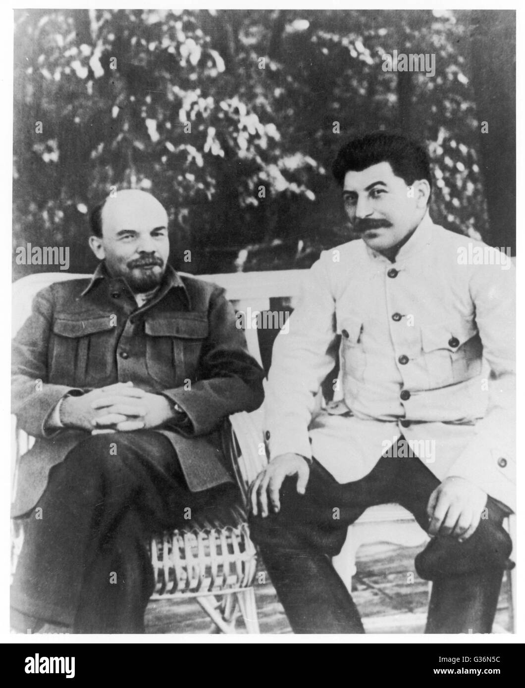 Vladimir Ilyich Lenin (1870 - 1924) and Josef Stalin (1879 - 1953), Communist Russian leaders, sitting on a bench.       Date: circa 1920 Stock Photo