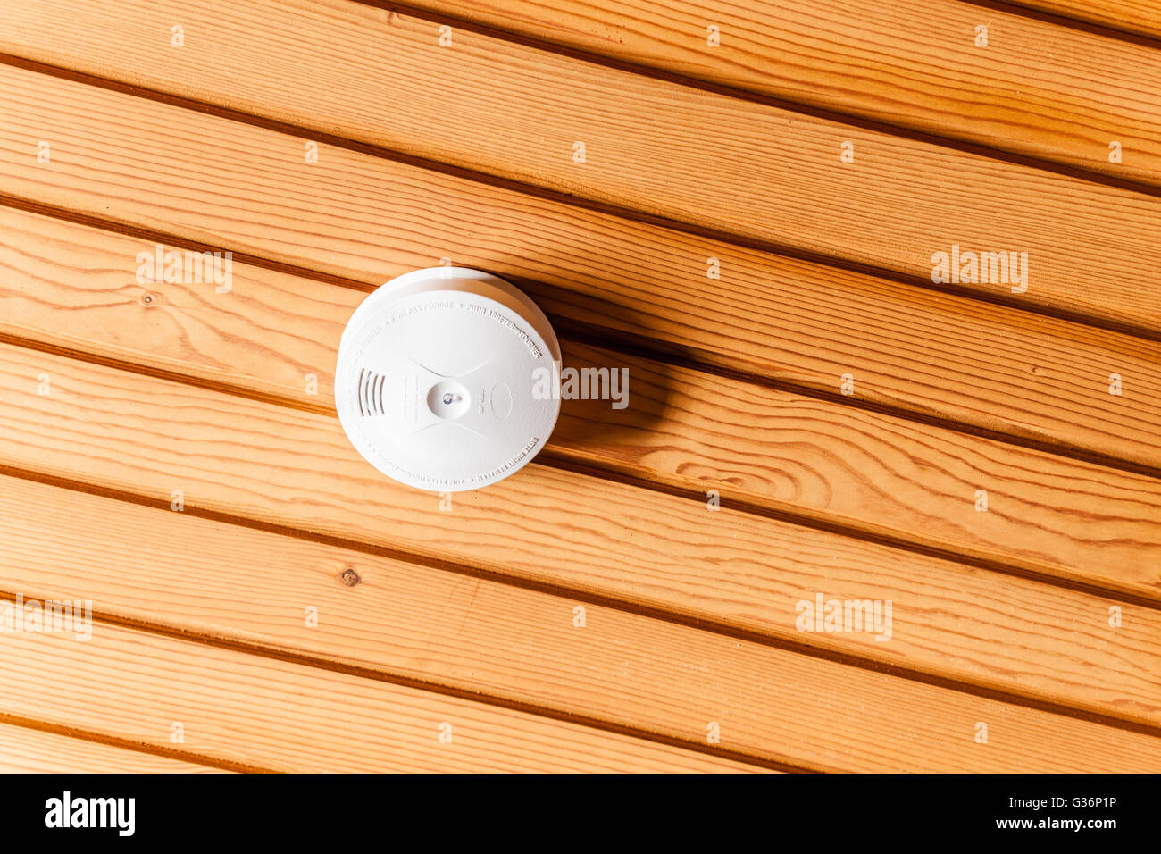 a white smoke detector attached to a wooden ceiling Stock Photo - Alamy