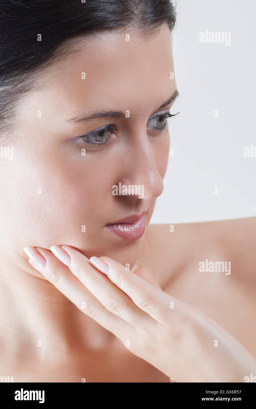 Beautiful young woman hand touching face looking away Stock Photo - Alamy