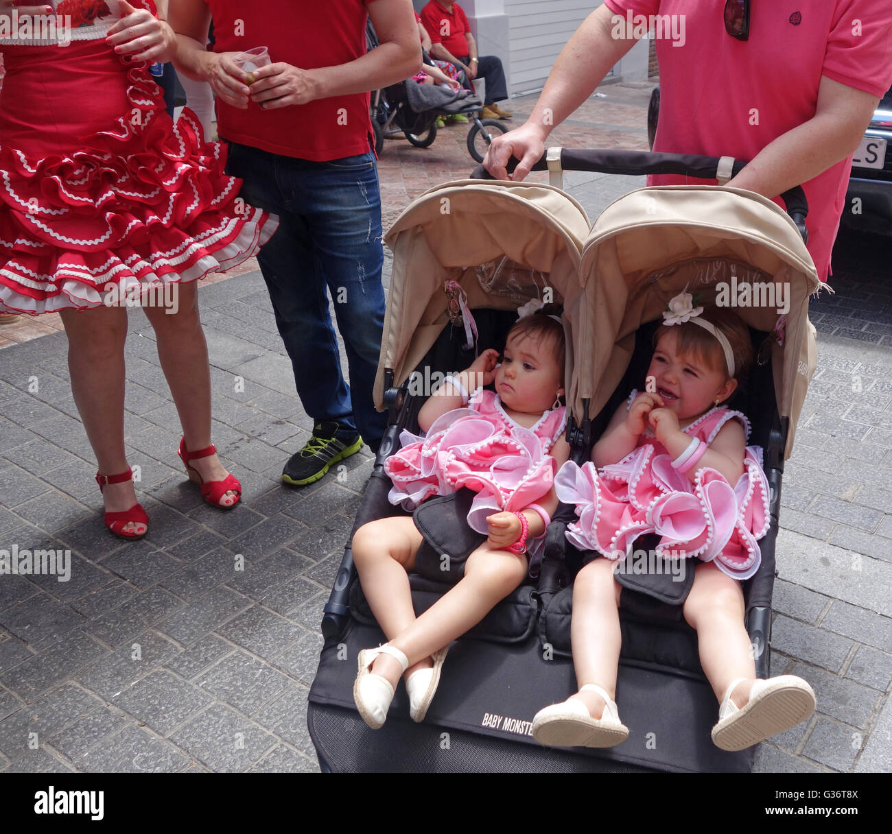 Twins twin girls dressed in pink traditional costume flamenco dancing in the street San Isidro festival fiesta in Nerja Andaluci Stock Photo