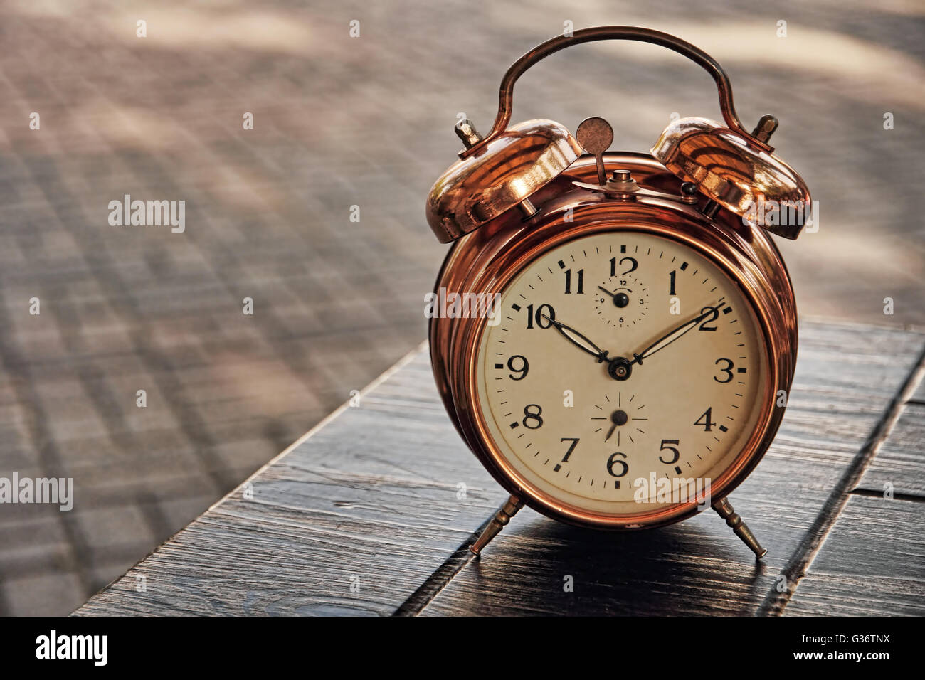 Vintage alarm clock on table and blurry background. Stock Photo