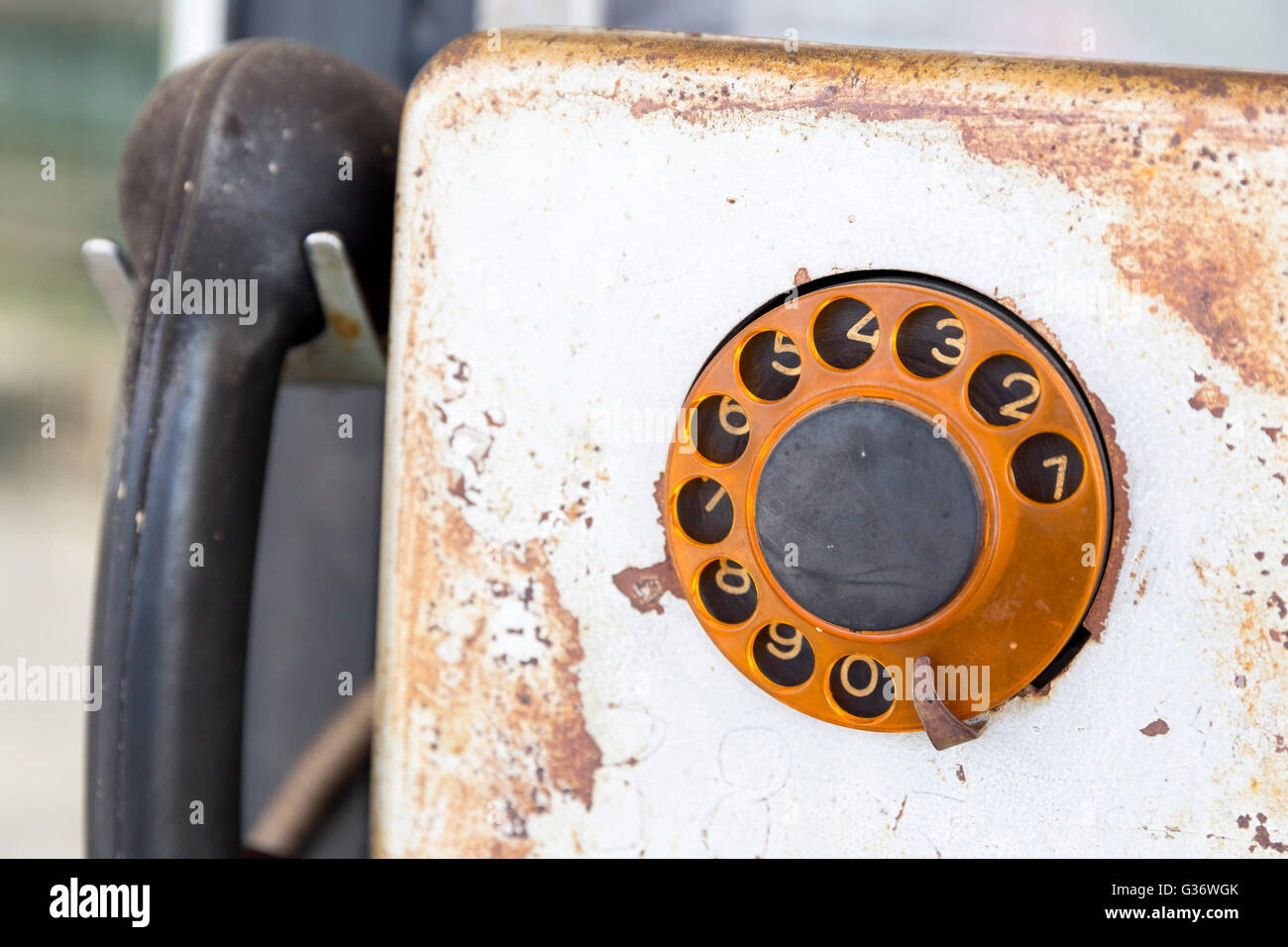 Rusty old vintage rotary pay phone for public use. Old pay telephone with coin slots on a wall. Stock Photo