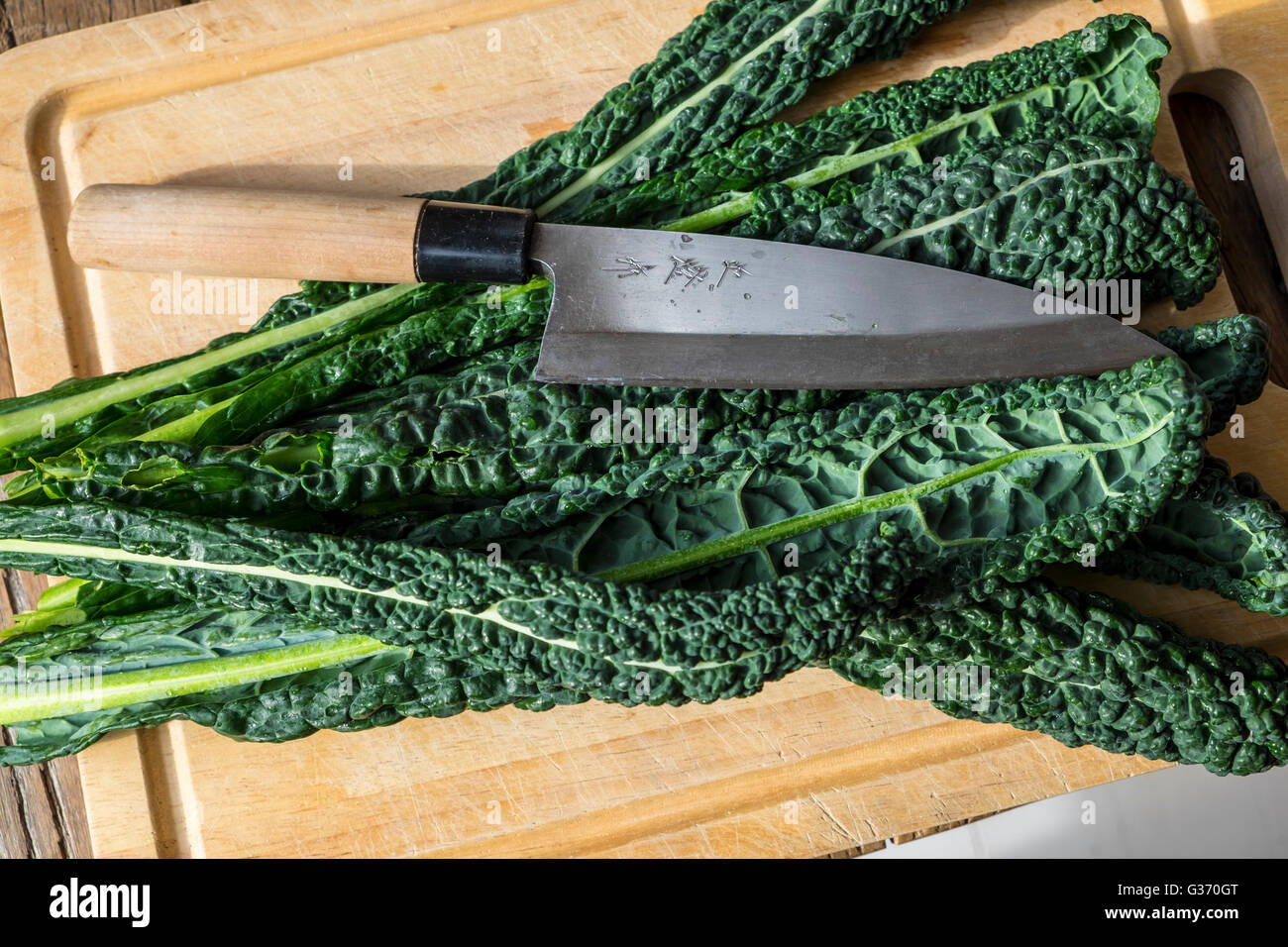 Tuscan kale on chopping board with Japanese knife Stock Photo Alamy