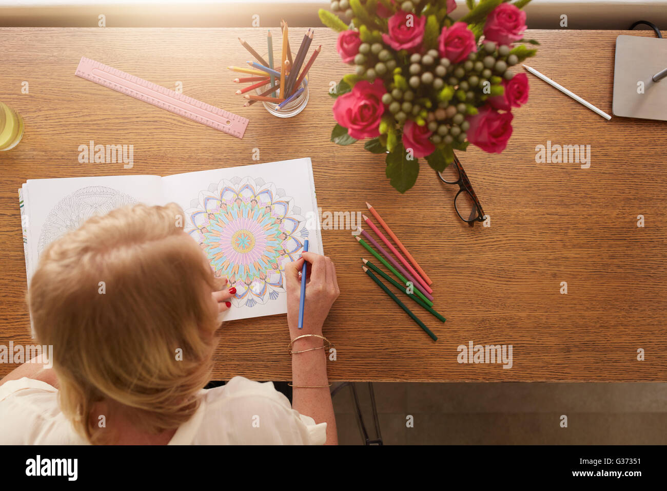 Top view of woman coloring floral designs with color pencils for relaxation at home. Anti stress adult coloring book. Stock Photo