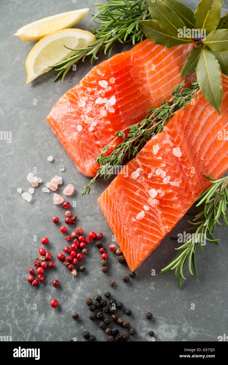 Salted fresh trout fillet with herbs, spices, and lemon wedges with copy space Stock Photo