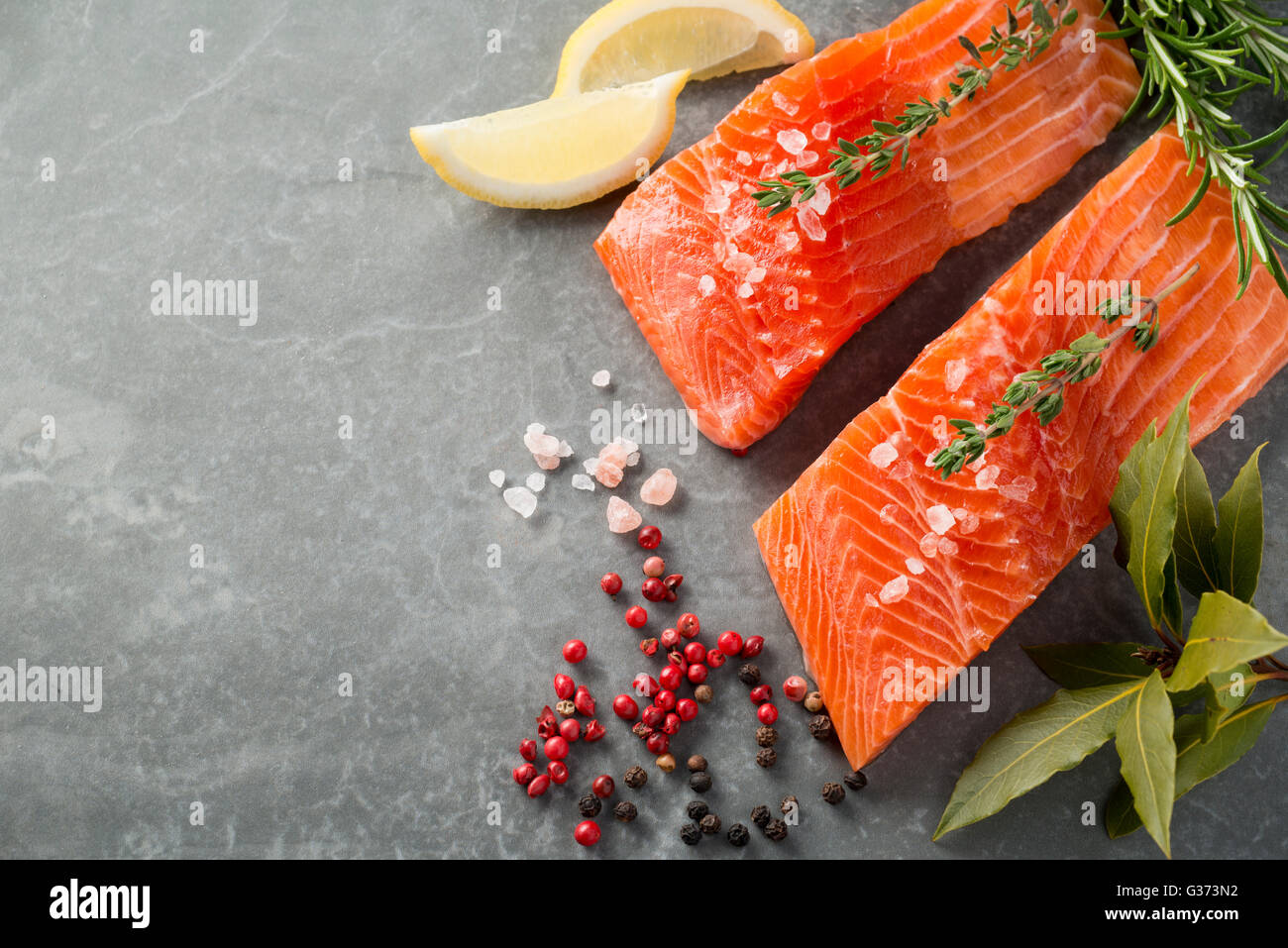 Fresh trout fillet with herbs, spices, and lemon wedges with copy space Stock Photo