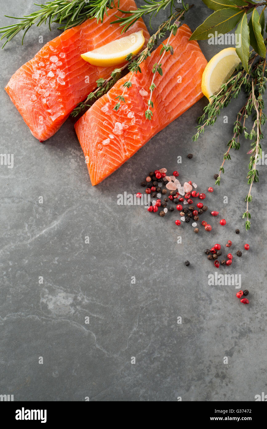 Fresh trout fillet sprinkled with herbs and spices on stone surface with copy space Stock Photo