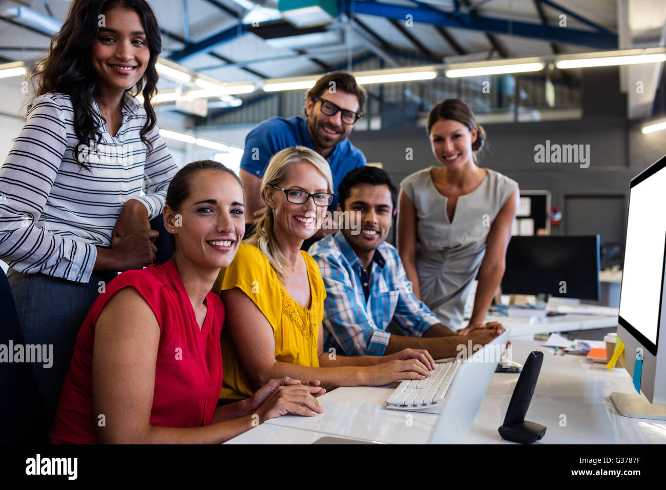Casual business team smiling at camera with arms crossed in the office ...