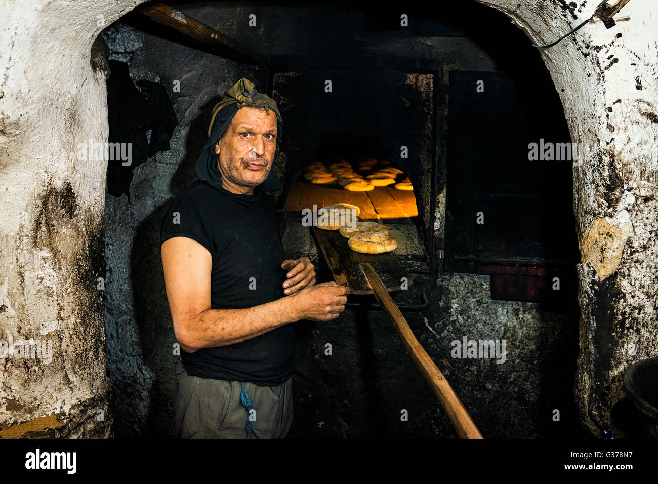 Fez, Morocco - April 11, 2016: Portrait of a baker standing in front of a traditional oven baking bread in Fez, Morocco. Stock Photo