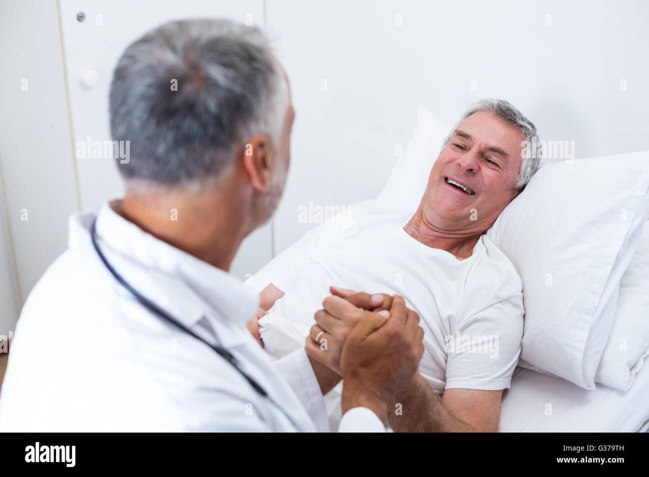 Male doctor consoling senior man Stock Photo