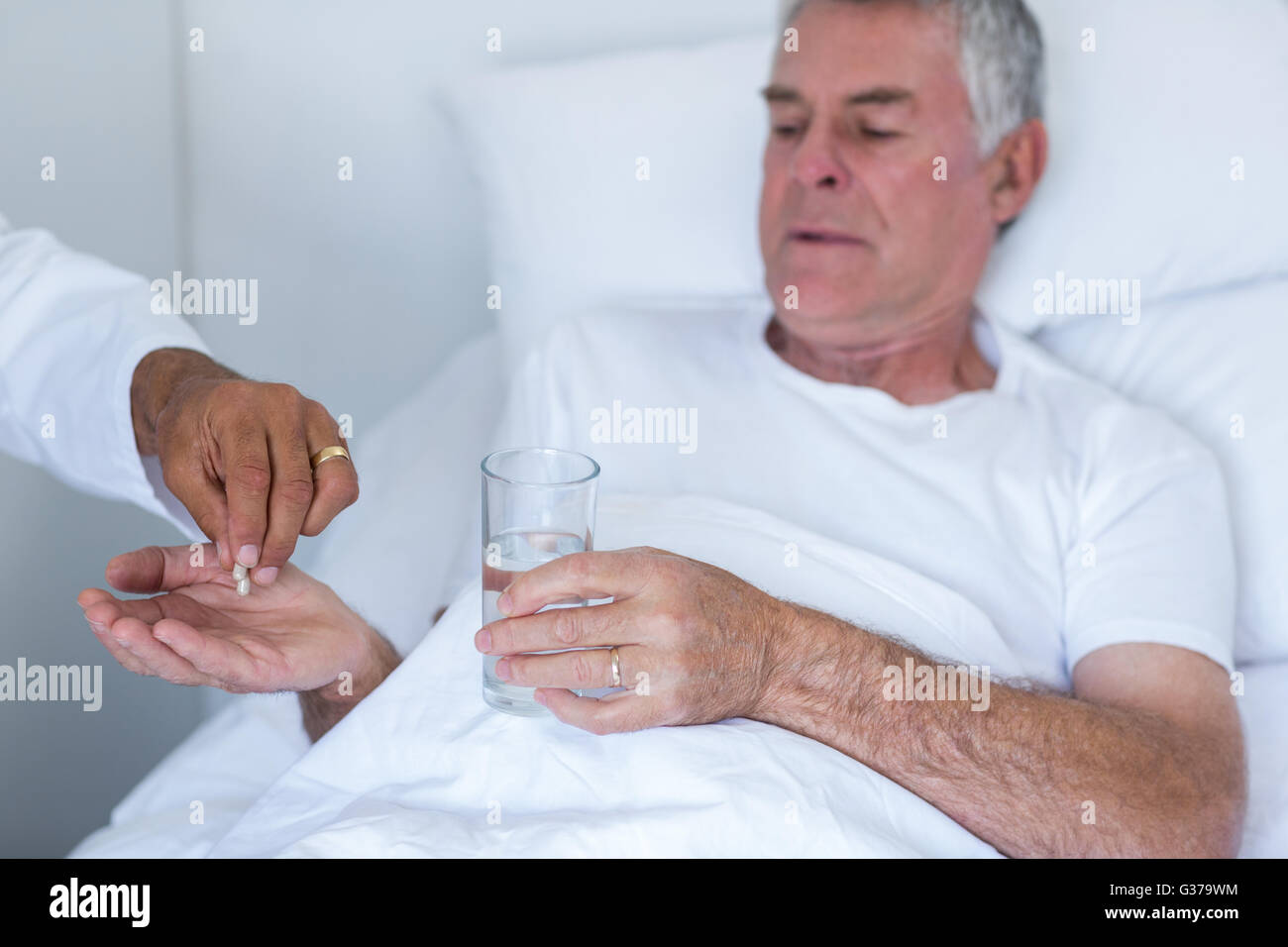 Male doctor giving pill to senior man Stock Photo