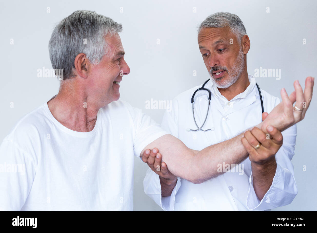 Male doctor giving palm acupressure treatment to senior man Stock Photo