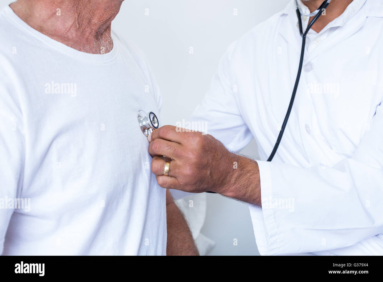 Male doctor checking heartbeat of senior man Stock Photo