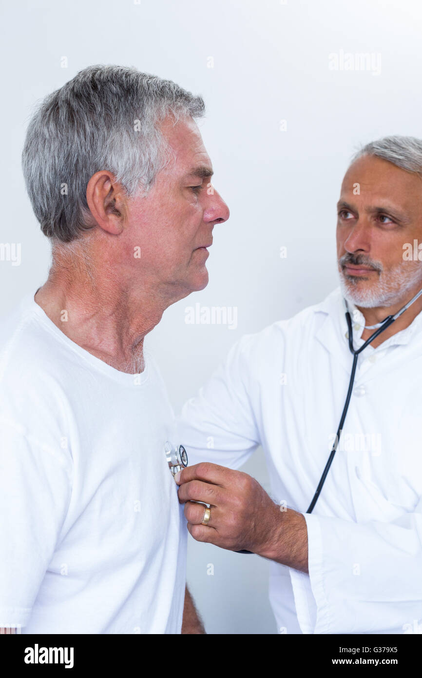 Male doctor checking heartbeat of senior man Stock Photo