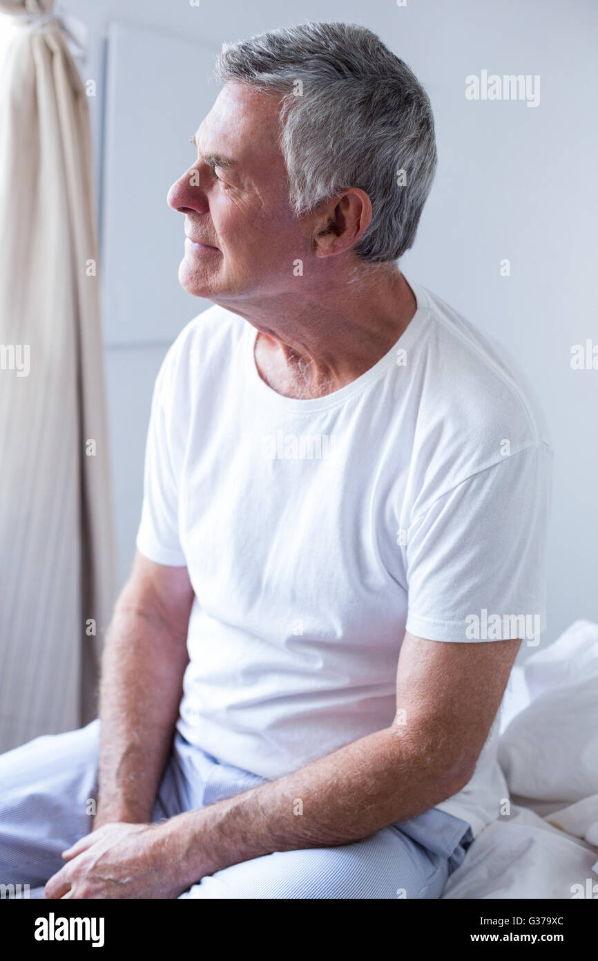 Thoughtful senior man sitting on bed in bedroom Stock Photo - Alamy