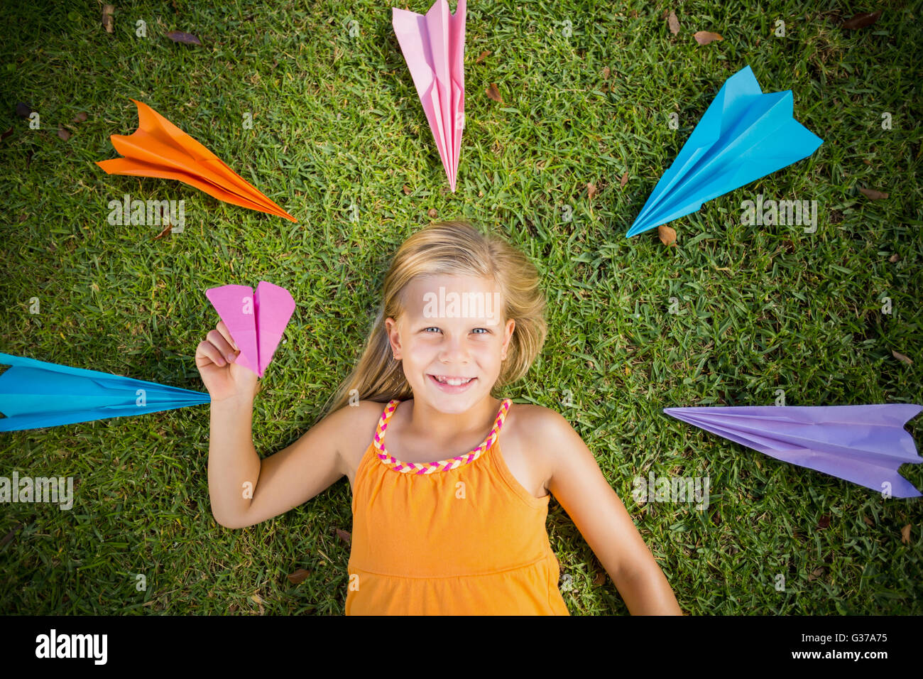 Young girl lying on grass around paper planes Stock Photo - Alamy