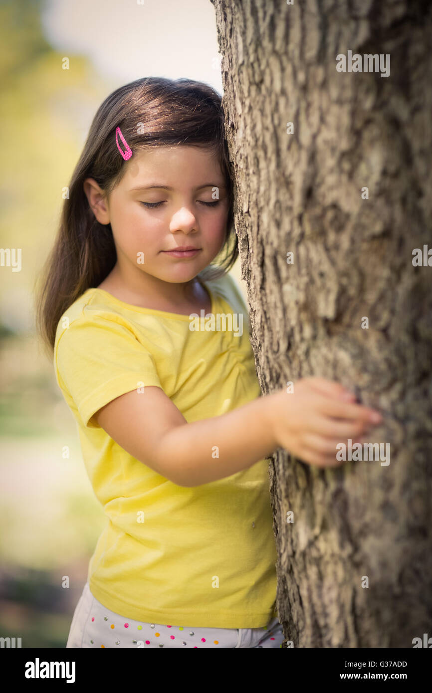 Thoughtful girl leaning on tree trunk Stock Photo